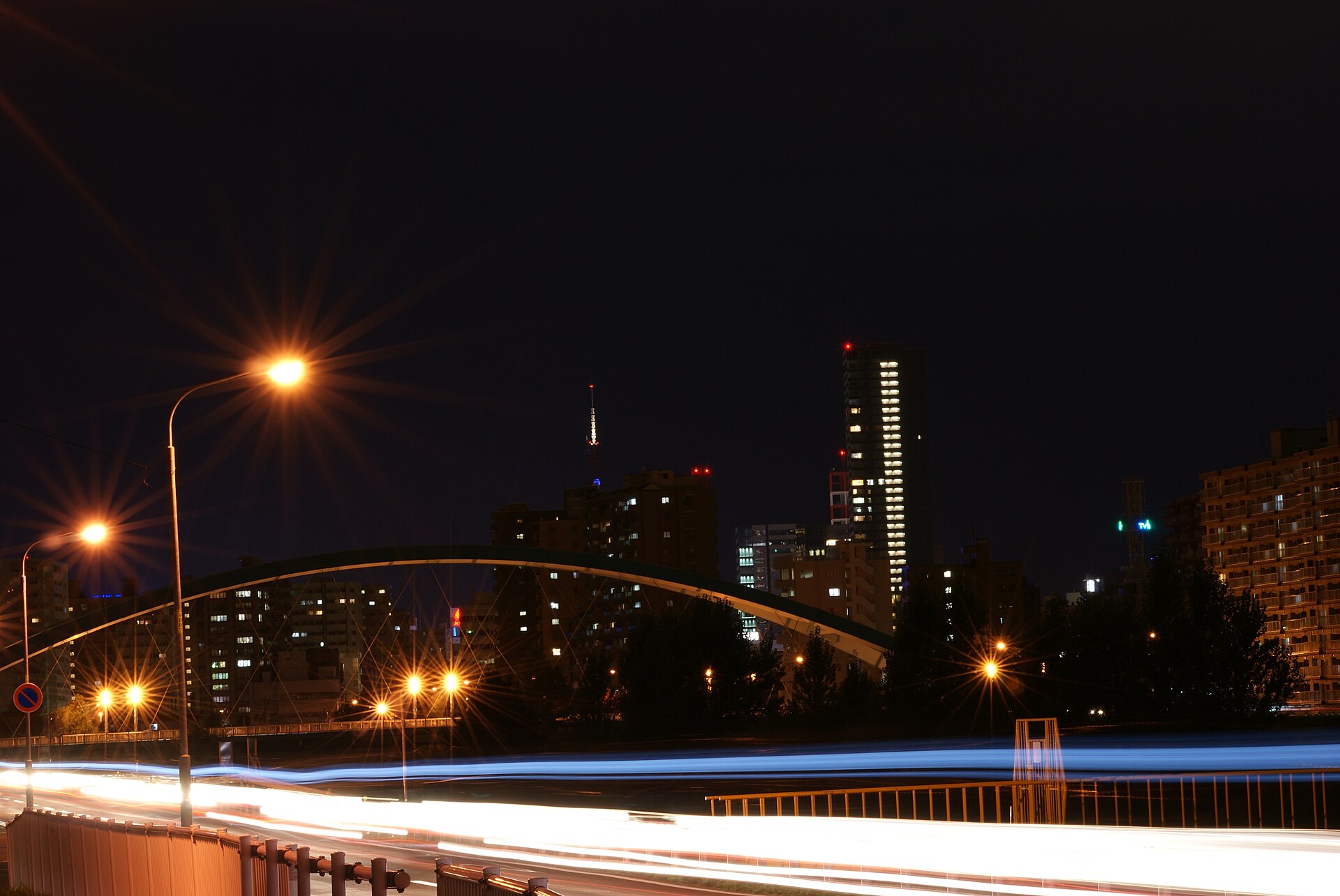 夜の豊平川沿いの道路とアーチ橋